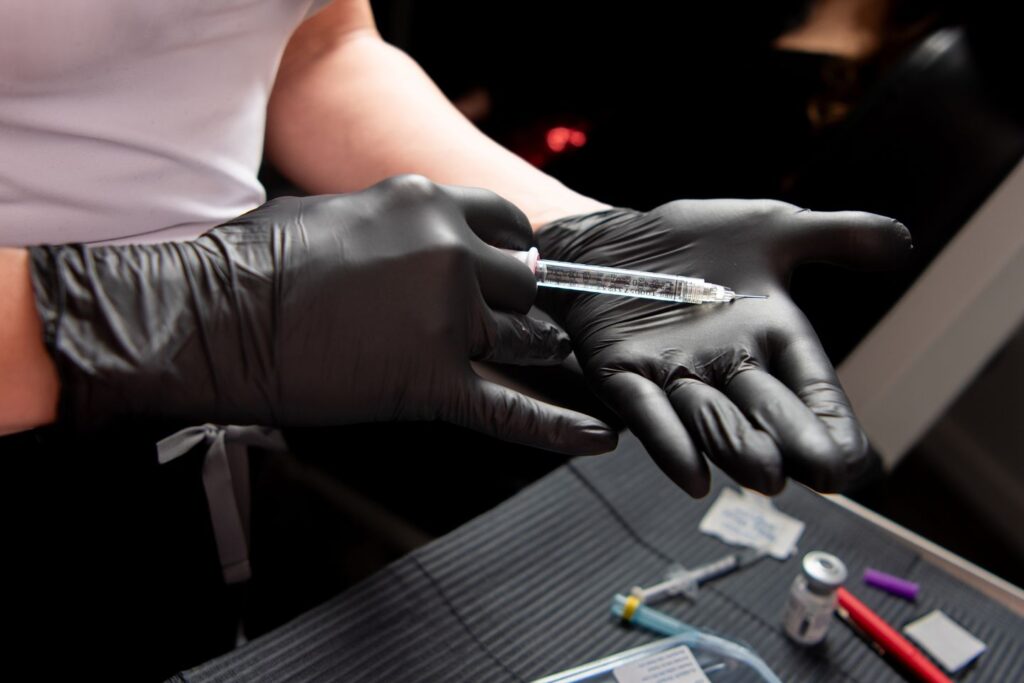 gloved hands preparing a syringe with Botox and Dysport vials in a clinic